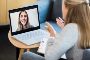 Person using a laptop for virtual therapy session.