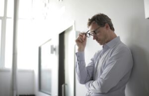 Man with his hands on his head, showing distress and signs of mental health issues.