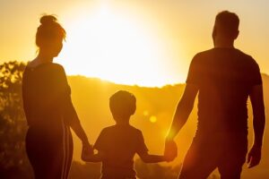 A family with their adopted child enjoying a moment together at sunset, symbolizing love, unity, and the beginning of a new chapter.