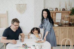 A mother and father bonding with their newly adopted child at a table, symbolizing love, support, and the beginning of their journey as a family.